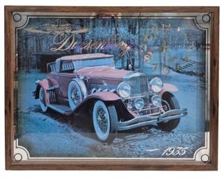 1431 - 1935 Duesenberg Automobile Wall Clock (Description): 21 x 27 - Wall clock featuring a classic car  design. The clock displays an image of a 1935  Duesenberg automobile with Duesenberg  branding. Presented in a wooden frame with  decorative corner details. Used as is electric/electronic/mechanical item. No  guarantee all components present, untested.