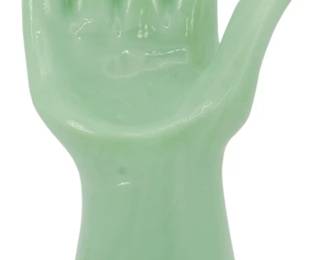147 - Jadeite Glass Hand Jewelry Holder 8" (Description): Jadeite glass hand figure in a classic  upright palm-open pose. The piece features  the distinctive opaque green color  characteristic of jadeite glass, with a  smooth, glossy finish throughout. The hand rises from a cylindrical base and displays  elegantly separated fingers. Measures 8  inches tall. Ideal for use as a ring holder,  jewelry display, or decorative accent.