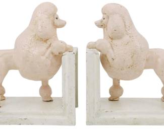 103 - Pr Cast Iron Poodle Bookends (Description): A pair of cast iron poodle bookends featuring  standing poodles in a classic show cut pose.  The poodles are painted in a soft pink or  blush color and mounted on white rectangular  bases with L-shaped book supports. The bookends display charming vintage character  with some age-appropriate wear to the painted  surfaces.