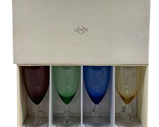2063 - Set of 4 Lenox Glasses in Box 9" (Description): A four-piece set of Lenox glasses presented  in their original box. The set includes  glasses in four distinct colors: amethyst  purple, green, blue, and amber, each  featuring a clear stem and foot. Each glass measures 9 inches in height.
