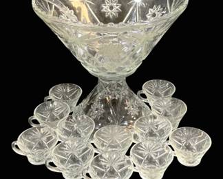 1552 - Pressed Glass Punch Bowl Set w/ Ladle & Cups (Description): Pressed glass punch bowl set featuring a  starburst or Early American Prescut pattern.  The set includes a large footed punch bowl  with beaded rim, matching glass ladle, and  approximately 12 matching punch cups with handles. The entire set displays coordinating  cut star and fan designs typical of  mid-century pressed glassware.