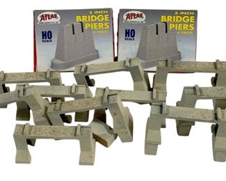 1062 - HO Scale Train Bridge Piers (Description): Pair of HO scale train bridge piers. Includes  two boxed Atlas 3 inch bridge pier sets  along with assorted loose bridge pier pieces  for model railroad layouts.