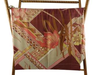 981 - Mid Century Folding Yarn Basket 18"x16"x9" (Description): Mid Century yarn basket featuring a wooden  folding X-frame with turned handle and brass  hardware. The fabric sling displays a vibrant  floral and geometric print in shades of  burgundy, coral, sage green, gold, and cream with iris and botanical motifs. Measures 18"  x 16" x 9".