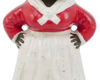 105 - Cast Iron Black Americana Bank 5.5" (Description): Cast Iron Black Americana bank featuring a  standing female figure with hands on hips.  The figure wears a red dress with white  collar and apron, white headscarf, and black  shoes. Measures 5.5 inches tall.