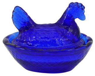 137 - Miniature Cobalt Glass Hen on Nest (Description): Miniature cobalt glass hen on nest dish. This  charming pressed glass piece features a  figural hen lid that sits atop a basket-weave  patterned nest base with scalloped edges.  The deep cobalt blue color is consistent throughout. Measures 2 inches by 2.5 inches  by 2 inches.