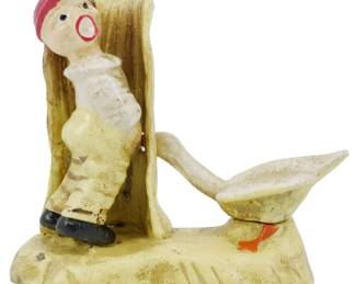 104 - Cast Iron Figural Boy & Goose Piece (Description): Cast iron decorative figure featuring a  painted scene of a young boy in a red cap,  white shirt, and yellow pants leaning against  a fence post while a white goose with orange  feet stands nearby with charming folk art appeal.