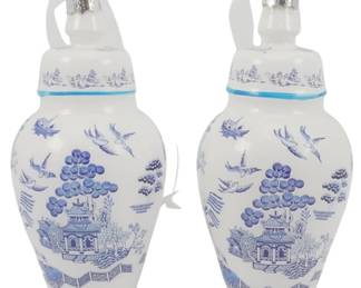 247 - Pair Blown Glass Chinoiserie Jar Ornaments (Description): A pair of Danny's Fine Porcelain Chinoiserie  jar ornaments in the classic blue and white  willow pattern style. Each ginger jar-shaped  ornament features traditional Chinese  landscape scenes with pagodas, trees, birds in flight, and boats, rendered in cobalt blue  on a white ground. The lidded jars have a  turquoise accent band at the neck and are  fitted with silver metal caps and hanging  loops for display.