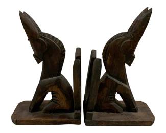 2337 - Pair Wood Bookends 10"x7"x3.5" (Description): A two-piece set of carved wood bookends  featuring stylized horse head figures. Each  bookend measures 10 inches by 7 inches by 3.5  inches.