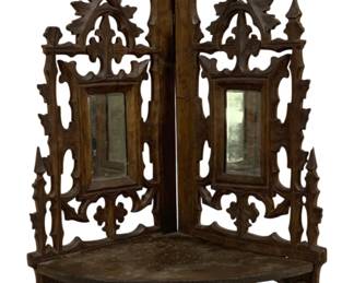 2106 - Victorian Walnut Carved Corner Shelf (Description): Wooden corner shelf featuring ornate carved  fretwork design with two small inset mirrors.  The piece has a Gothic-inspired aesthetic  with decorative scrollwork and pointed  elements. Measures 19.5 inches by 12 inches by 8 inches.