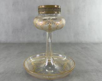 An antique Bohemian cut crystal rose bowl / flower frog vase, 10-3/4" tall, featuring a classical footed center bowl or posy design elevated by a pedestal stem, decorated with engraved and gold gilt flower garlands. The top is fitted with an ornate, removable metal filigree rim holding a woven wire mesh "frog", which is used to support and organize flower stems. Produced by the historic Josephinenhütte glassworks around the late 19th century to early 20th century (circa 1900.)