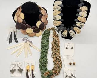 A multi-strand statement necklace made from Tagua Nut slices (also known as vegetable ivory) in alternating shades of cream, tan, and dark brown; a statement necklace of alternating pebble-shaped Picasso Jasper stones and matte black spacer beads; A multi-strand micro-bead necklace woven together in a thick braided torsade design; a variety of artisan handmade earrings