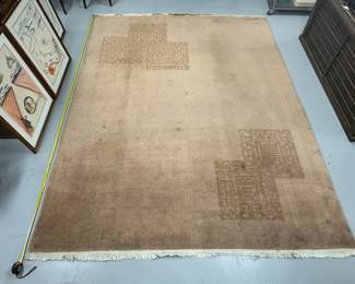 A Chinese/Art Deco-inspired geometric rug featuring a neutral beige-camel color wool pile with stylized corner shou-style geometric motifs and fringed ends. Measures 8'10" x 11'10"