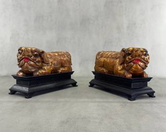 A pair of carved and lacquered gilt wood fo dogs or lions, on black lacquered wooden bases, each  made in China. Each is 4-1/2"W x 7"H x 10-3/4"L.