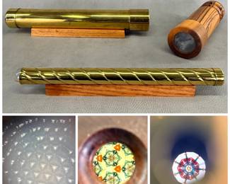 More views of the brass spiral kaleidoscope, 12-1/2" length, on a small wooden display stand; a handcrafted, hand-turned zebrawood barrel kaleidescope approximately 9-1/2" tall, and a large brass cylindrical kaleidoscope with wooden stand, approximately 14" long.