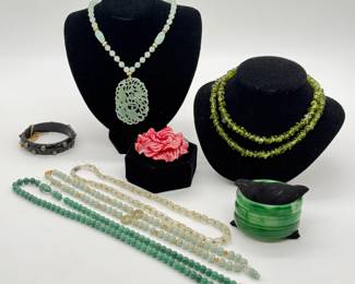 A variety of jade and natural hardstone beaded necklaces (one jade with 14K gold clasp), a double strand polished peridot chips necklace, a jade necklace with 14k clasp and carved openwork pendant; Peking glass bracelets, a vintage Fabrice Resin Camellia brooch, and a 1930's bakelite black bangle bracelet