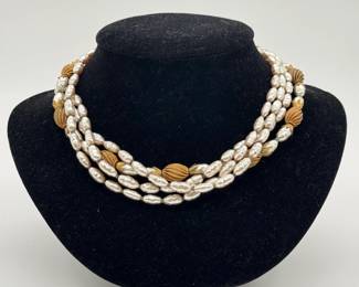 A vintage Miriam Haskell three-strand faux pearl necklace featuring rice or baroque-shaped glass pearls accented by ribbed, melon-shaped gold-tone beads and decorative petal caps. 14” length; Miriam Haskell stamp on the clasp.