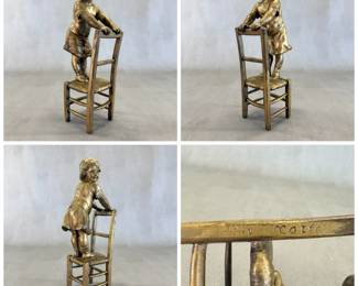 A vintage cast metal sculpture, in the style of Juan Clara, of little girl standing on chair, resting her hands on the back of the chair. 12" tall.