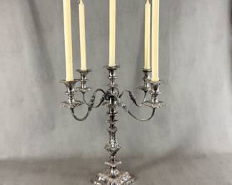 An exquisite antique silver plated five-light candelabra featuring four gracefully extending S-scroll arms adorned with applied stipple and chased leaf motifs, culminating in foliate repoussé drip pans and baluster-shaped candle cups with matching foliate-chased bobeches. The central candle cup crowns the highly ornamented standard. The five-light section is removable so that the baluster form base, richly embellished with foliate scrollwork, can be used as a single candlestick! Maker's mark to the underside of the five-light section, where it fits into the base. 18-1/2"Wx 19"H.
