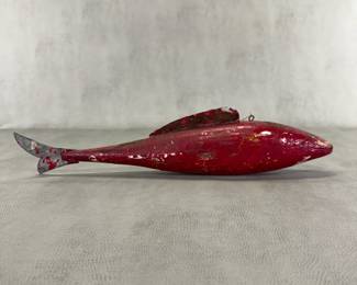 An exceptionally large 19-1/2" long vintage hand-carved ice fishing fish decoy - classic North American rustic folk art - with hand-carved wooden body, a metal dorsal fin, a metal tail fin, and a line-tie eyelet on top. Displaying original (now heavily crazed) crimson red paint, this large-scale decoy was carved specifically to lure massive lake sturgeon or trophy-sized muskellunge.