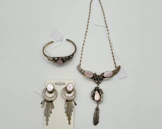 Native American/Southwestern silver jewelry - a sterling silver necklace featuring pink mother-of-pearl (or pink shell) cabochons, floral and leaf motifs, and a dangling feather charm; a sterling silver and pink mother-of-pearl cuff bracelet, and pair of unmarked silver  pink mother-of-pearl dangle earrings featuring oval pink mother-of-pearl (MOP) cabochons, stacked circular silver frames, and cascading fringe bar accents.
