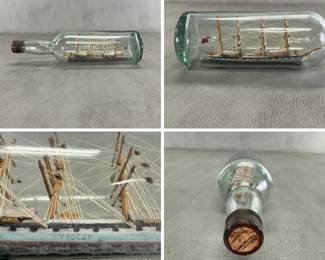 A vintage ship-in-a-bottle folk art diorama featuring a four-masted sailing ship encased inside a glass bottle