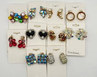 A vintage collection of mid-century clip-on costume jewelry earrings, including multi-colored floral rhinestone clusters, aurora borealis crystals, faux pearls