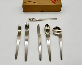 Iconic Arne Jacobsen stainless steel flatware place setting designed in 1957 for Georg Jensen, famous for its sleek, minimalist lines and fluid integration of handle and bowl; with original packaging