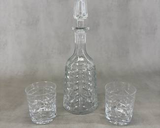 A Tiffany & Co. "Swag" crystal decanter with stopper, and two double old fashioned glasses, handcrafted by the renowned British manufacturer Royal Brierley. Decanter with stopper 12" tall, glasses 3-1/2” tall.
