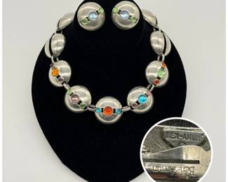 A vintage Ben-Amun statement jewelry set featuring high-polished, chunky silvertone domed link construction with a distinct architectural, space-age flair, the domed segments set with multi-colored glass cabochons in varying sizes; the necklace is 16” long and comes with matching earrings. 