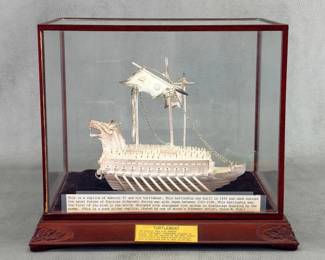 A 99.0% silver model of the Korean turtle ship the Keo Buk Seon (Geobukson) designed by Admiral Lee Sun Shin and used against the naval forces of Japan during the war with Japan 1592-1598. The model rests on crimson velvet in a hand-crafted wooden display case with carved foliate embellishments and removable wooden-framed glass top. Total height of case 10 inches high.