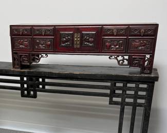 An antique hardwood Chinese lady's chest or scholar’s cabinet (a low kang cabinet) with six small drawers and central cupboard; with relief carvings of flowers, baskets of peaches, incense burners; dimensions 42.5”W x 13.5”H x10”D