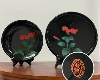 Traditional Ryukyu lacquerware tray and dish from Okinawa, Japan, featuring a raised, carved red hibiscus flower against a glossy black background.