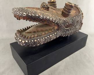 a vintage African cowrie shell and seed-mounted wood alligator or crocodile head headdress or mask, frequently associated with ceremonial traditions in West or Central African cultures.