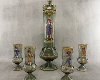 A stunning antique Bohemian glass pokal set from the late 19th century, consisting of a dark green glass lidded, footed, narrow tankard with handle, decorated with elaborate polychrome enamel paintings of Renaissance-era Landsknecht soldiers, and a matching set of four smaller footed beakers. The tankard—with lid—is 22 inches high! Each beaker is approximately 7-3/4” H.