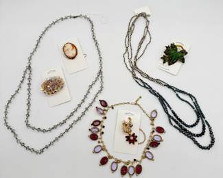 A vintage mid-century oval cluster brooch featuring faceted glass and crystal beads with an iridescent Aurora Borealis (AB) finish; a vintage gold-tone swirl brooch - curved, leafy swirl stem set with clear rhinestones and suspending a ruby-color marquise-cut crystal flower with clear rhinestone center; a 1960’s light and dark purple cabochon dangle necklace; a 1960’s Exquisite ivy leaf brooch featuring hand-enameled green and brown finishes over gold-tone metal, made in England W.A.P. Watson for Exquisite Jewellery Ltd., and more costume jewelry necklaces