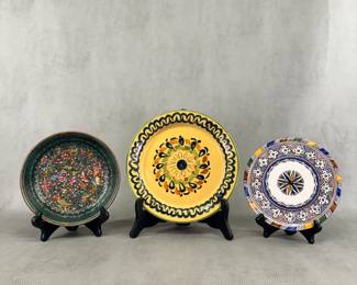 A hand-painted butterfly and flowers decorative dish from Michoacán, Mexico, 7-⅛”W; a vintage yellow glazed ceramic plate featuring hand-painted floral design center and black wavy rim border, 9”W, and a traditional, hand-painted Moroccan ceramic plate or wall platter featuring multi-colored geometric and star motifs, 7”W.