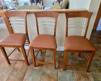 wooden bar stools with upholstered brown vinyl seats and ladder-style backs