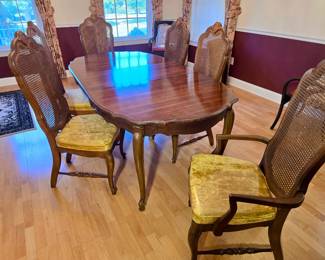 vintage walnut dining table and matching cane-back chairs that resemble mid-century French Provincial