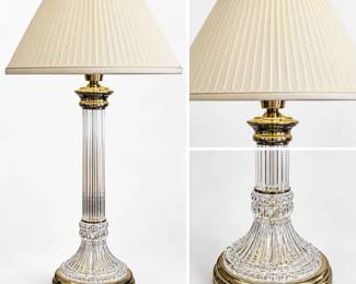 Elegant crystal glass table lamp featuring a tall fluted glass column rising from an ornate pressed and cut-pattern glass pedestal base. Polished brass-tone fittings accent the base, column and upper lamp assembly, creating a classic formal appearance. Finished with a coordinating clear glass finial and large ivory pleated shade. Substantial traditional lamp well suited for a living room, bedroom, library or formal interior. Pre-owned condition with light wear consistent with normal use; please review photographs for condition and details.