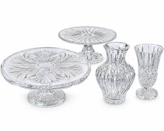 Elegant four-piece clear crystal collection featuring two pedestal cake stands or serving plates and two decorative vases in complementary cut and pressed crystal patterns. The larger pedestal stand features a dramatic radiating starburst and floral design with a substantial footed base, while the smaller stand displays a coordinating radiating pattern. Also included are a rounded baluster-form vase with deeply cut vertical decoration and a tall footed vase with fluted sides and diamond-cut detailing. A versatile grouping for formal entertaining, wedding or holiday tables, floral arrangements, dessert presentation or decorative display. Maker and pattern have not been confirmed. Pre-owned condition with expected signs of previous use; please review photographs carefully for condition, clarity, edges and decorative details.