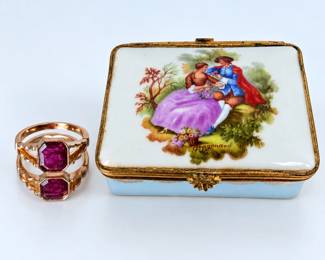 Elegant 14K gold and ruby ring presented with a vintage porcelain jewelry or trinket box decorated with a romantic courting scene after Jean-Honoré Fragonard. The ring features a richly colored faceted ruby in an octagonal form, secured in a gold bezel-style setting with attractive openwork split shoulders. Ring measures approximately size 5 based on the sizing photograph. Accompanying porcelain box features a pale blue body, hand-decorated style romantic scene signed “Fragonard,” ornate gilt metal mounts and decorative clasp. A particularly attractive presentation combining fine jewelry with a decorative vintage keepsake box. Vintage condition with age-related wear and patina to the box and metal mounts; please review photographs carefully for condition and details. Ruby specifications, including carat weight and treatment, have not been independently verified unless otherwise stated.