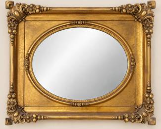 Impressive decorative mirror featuring an oval mirror plate set within an elaborate rectangular gilt frame. The richly ornamented frame features raised floral and fruit motifs at the corners, scrolling foliate decoration, beaded and molded borders, delicate floral accents surrounding the oval mirror and a distinctive textured gilt ground. The aged gold-tone finish displays attractive tonal variation, patina and darker detailing that emphasizes the dimensional ornamentation. Overall measurements are approximately 33 inches tall x 39 inches wide. Pre-owned condition with age-related wear including areas of gilt and finish loss, rubbing, surface marks, cracking and crazing to the decorative finish, and scattered wear to the raised ornamentation. Existing patina, wear and imperfections have not been restored or concealed. Please review all photographs carefully for construction, finish and condition. No maker, specific age or country of origin has been confirmed.