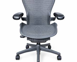 Authentic Herman Miller Aeron ergonomic office chair featuring the iconic breathable mesh seat and back, adjustable padded armrests, contoured ergonomic frame, five-star rolling caster base, and rear lumbar support system. Herman Miller branding is clearly present on the chair. Multiple adjustment controls allow the chair to be configured for comfortable desk and office use. Pre-owned condition with visible surface scratches, scuffs, and wear to portions of the frame and adjustment components, as shown in the photographs. Mesh appears generally well maintained from the photographed views. Adjustment mechanisms have not been independently tested through their complete range. Identification numbers and additional markings are photographed for reference. Please review all photographs carefully for condition, features, and details. Sold as photographed.