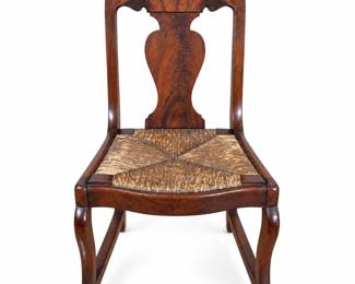 Antique wooden rocking chair featuring a striking figured wood back with broad shaped crest and distinctive vase-form central splat. The chair is fitted with a hand-woven rush-style seat arranged in an attractive geometric pattern, gently shaped front rail, curved front legs, and long traditional rocker rails. Rich dark finish and dramatic wood grain give the chair strong visual character. Measures approximately 31 1/2 inches tall overall with a 16 1/2-inch seat height. Antique/pre-owned condition with surface scratches, finish wear, rubbing, discoloration, and other age-related marks consistent with use. Woven seat shows age and wear as photographed. Exact maker, wood species, age, and country of origin have not been independently identified. Please review all photographs carefully for construction, condition, and details. Sold as photographed.