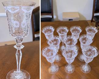 Elegant set of eleven matching crystal wine goblets featuring an elaborate floral and draped garland motif surrounding the bowls. Each glass has a gently flared rim, elongated faceted stem with geometric detail, and a striking radiating starburst-cut foot. The intricate decoration and graceful proportions give the stemware a refined, formal appearance well suited for entertaining, holiday table settings, weddings, or a vintage crystal collection. Maker and pattern have not been confirmed. Pre-owned condition with light wear consistent with age and use. Please review photographs carefully for pattern, condition and details.
