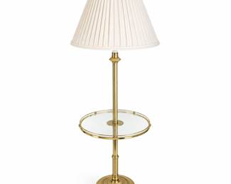 Elegant vintage brass-tone floor lamp featuring an integrated round glass side table, polished column-style standard, decorative fluted details, and a substantial stepped circular base. The glass table is surrounded by a brass-tone gallery rail, creating a practical combination lamp and occasional table ideal for use beside a chair, sofa, or bedside. Finished with a classic pleated cream fabric shade and decorative ring finial. The brass-tone finish shows light surface wear and signs of previous use consistent with age. Glass may exhibit minor surface wear. Electrical components and long-term functionality have not been independently tested. Maker and exact age have not been identified. Please review all photographs carefully for construction, finish, and condition. Sold as photographed.