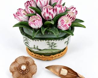 Charming vintage decorative grouping featuring an ornate porcelain floral arrangement with dimensional pink and white tulip blossoms and green leaves set within a hand-decorated porcelain vessel. The vessel features green landscape and Asian-inspired scenic decoration with gilt-tone ornamental trim and base. Accompanied by two vintage floral brooches/pins in gold-filled and/or gold-tone metal. One is an intricate openwork filigree flower design centered by a pearl-like cabochon; the second is a sculptural leaf-form brooch with textured surface and a dimensional ivory-tone floral accent. Pins have not been individually tested for precious-metal content and are described as gold-filled or gold-tone based on appearance and visible markings. An attractive collection of vintage floral decorative arts and costume jewelry with strong display appeal. Please review all photographs carefully for markings, construction, condition, age-related wear and additional details.