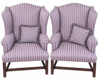 Matching pair of upholstered wingback armchairs featuring elegant dusty lavender and muted purple striped fabric, gracefully shaped wing backs, rolled arms, and dark-finished wood legs with stretcher bases. Each chair includes a coordinating geometric-pattern decorative pillow with fringed trim. The classic silhouette and sophisticated purple palette work well with traditional, transitional, or contemporary interiors. Upholstery presents attractively overall with light signs of previous use visible upon close inspection; wood bases may show minor surface wear consistent with use. Please review all photographs carefully for fabric, construction, and condition. Maker and fabric composition have not been independently identified. Sold as a pair with the pictured pillows.