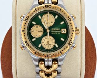 Vintage Seiko Chronograph Sports 100 men’s wristwatch featuring a striking deep green dial with gold-tone subdials, luminous-style hour markers, date window, alarm function and two-tone silver and gold-tone case and bracelet. Case back is marked Seiko, Water Resistant 10 Bar, Movement Japan and Cased in Korea; please refer to photographs for all additional numbers and markings. The watch shows visible surface scratches, finish wear and other signs of previous use consistent with its vintage estate condition. Functions and service history have not been independently verified. Sold as an estate watch in its present condition; photographs are considered part of the condition description.