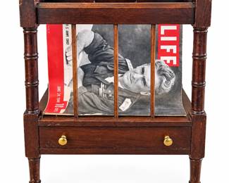 Vintage dark-finished wood magazine rack or Canterbury-style stand featuring turned corner posts, spindle dividers, shaped upper rails with integrated carrying handle, and a lower storage drawer fitted with two brass-tone knobs. Raised on small brass-tone casters for easy movement. Includes the pictured vintage June 24, 1940 LIFE magazine and additional magazines stored within the rack. The piece displays attractive traditional styling and age-related character. Condition shows visible surface scratches, finish wear, rubbing and other signs of age and use; the drawer interior shows notable wear and finish loss as photographed. Exact maker, wood species, and age have not been independently identified. Please review photographs carefully for condition and details. Contents shown are included.